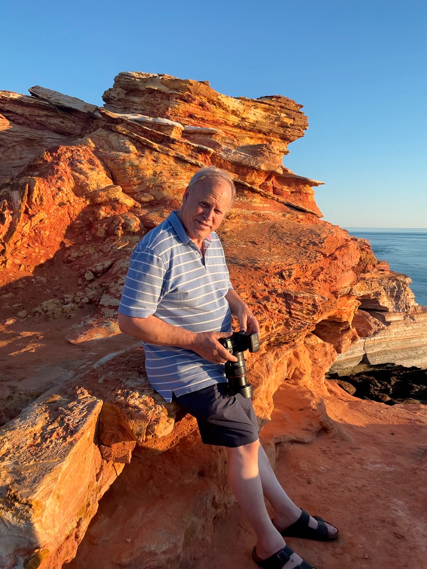 David Godfrey of Gotham Studios Collective standing on a rocky outcrop with ocean view