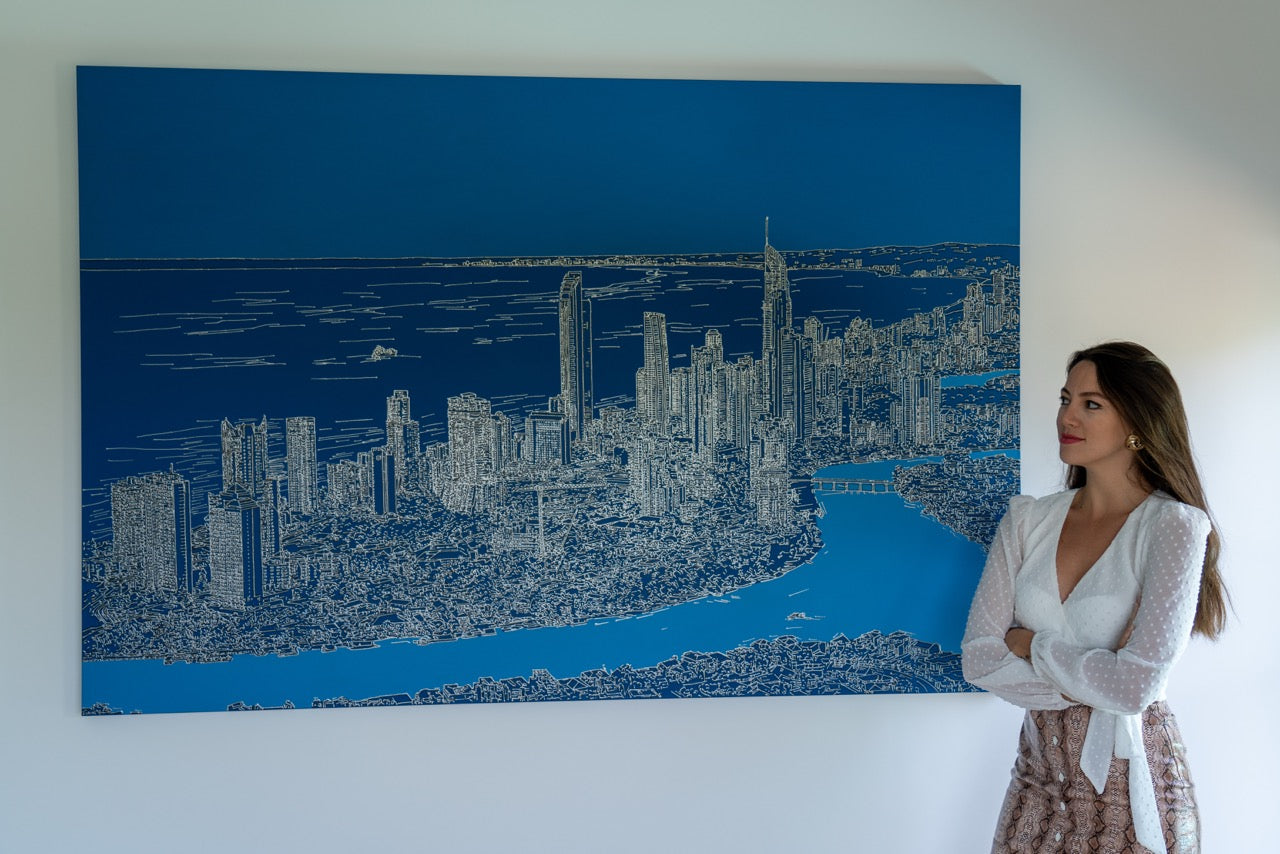 Sebnem Gencer of Gotham Studios Collective standing in front of a large painting of a city skyline.